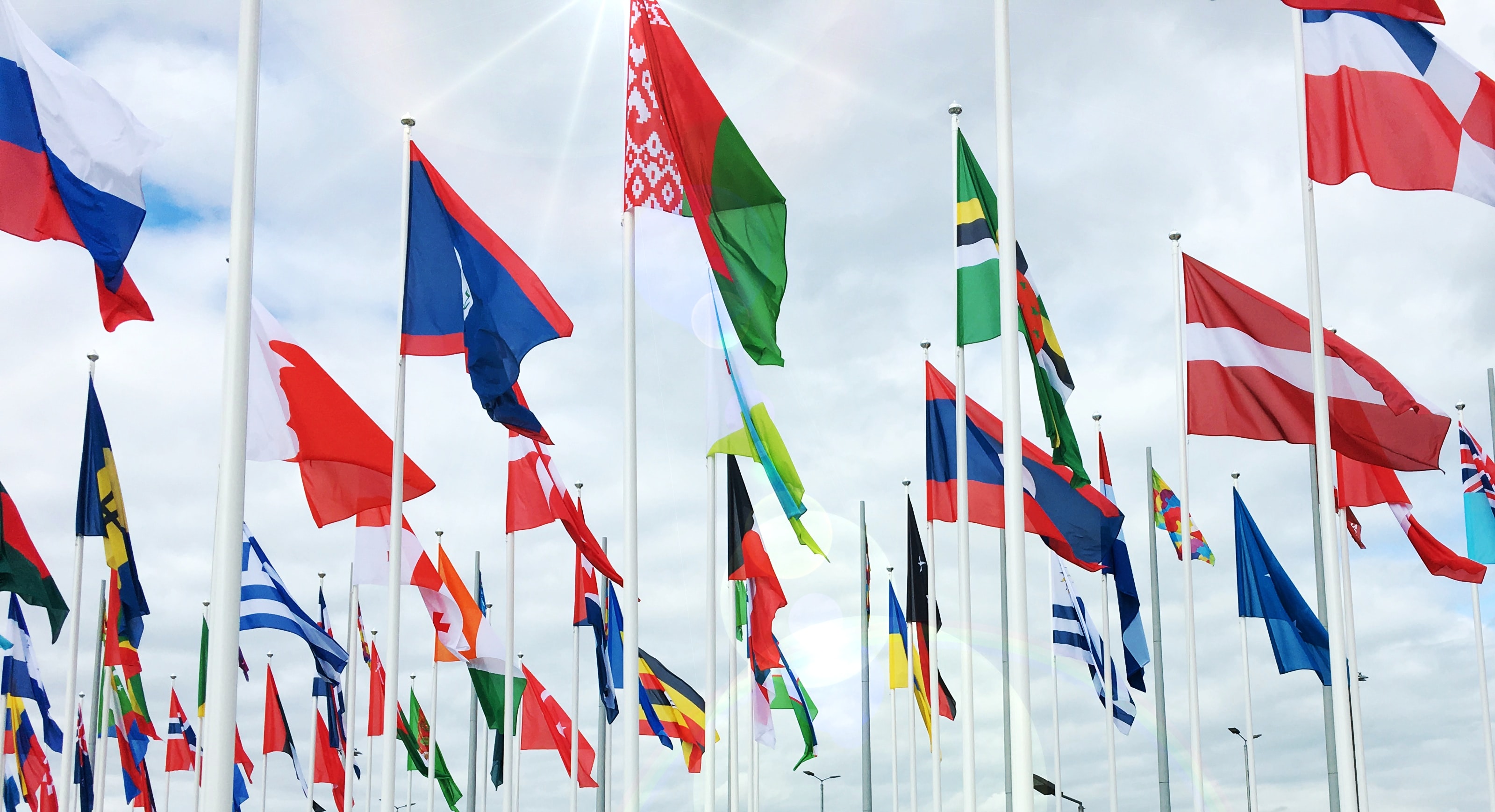 A scene featuring a collection of international flags against a backdrop of the sky